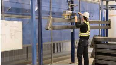 An employee uses a Gorbel G-Force intelligent lifting device to lift a grain bin foundation.
