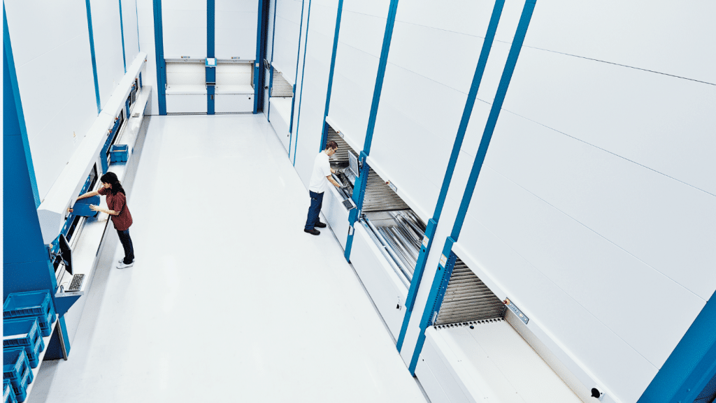 People work alongside vertical lift modules in a warehouse.