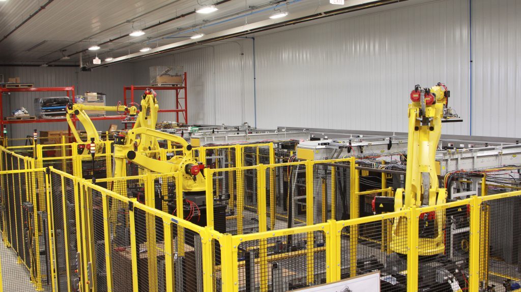 Industrial robots in work cells in a warehouse.