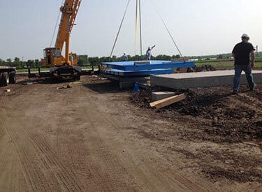 A crane operator installs an industrial scale.