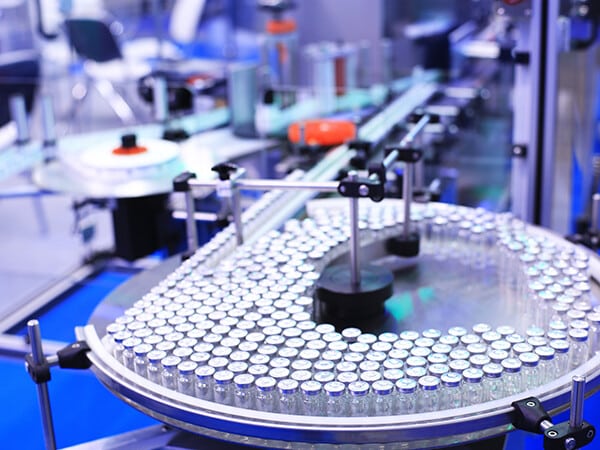 Vaccine bottles are moved on a conveyor system.