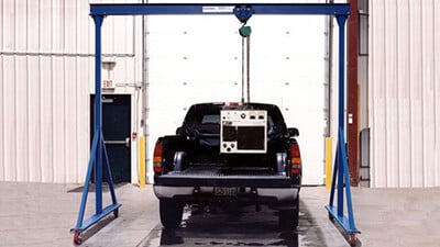 A Gorbel gantry crane is used to move a heavy item into a truck bed.