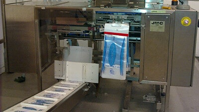 A JMC automated wicketted bulk bagger machine opens and fills pre-made poly bags.