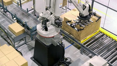 A palletizing robot stacks cartons on a pallet on a conveyor system.