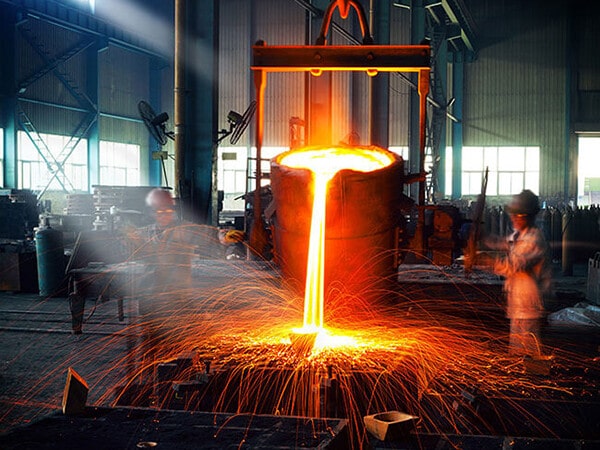 Workers in a foundry pour molten metal.