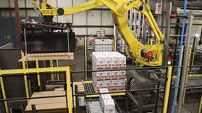 A palletizing robot lifts and moves a full pallet.