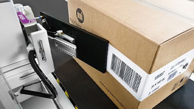 A machine applies a label to a carton.