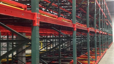 Red and green pushback racking is shown in a warehouse.
