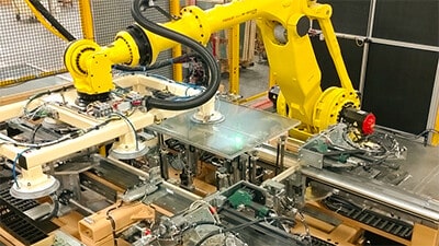 An industrial robot applies sealant to products on a conveyor line.