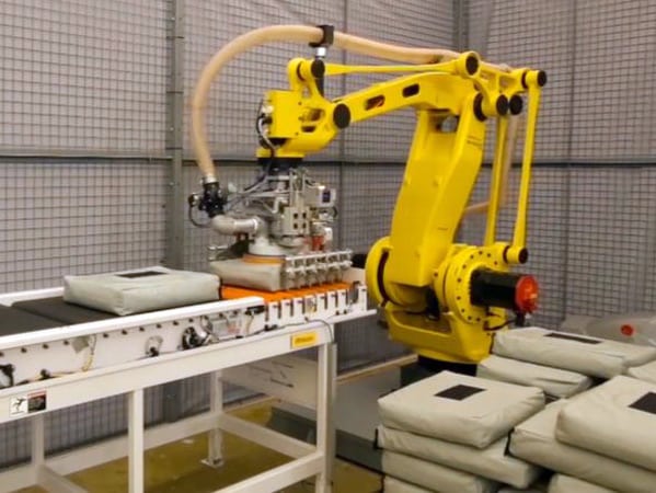 A robotic bag palletizer stacks bags on a pallet.