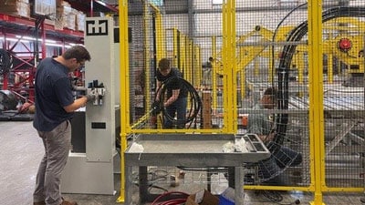 Workers in a warehouse near a robotic cell.