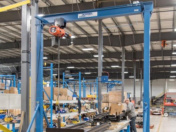 A blue Gorbel gantry crane in a warehouse.