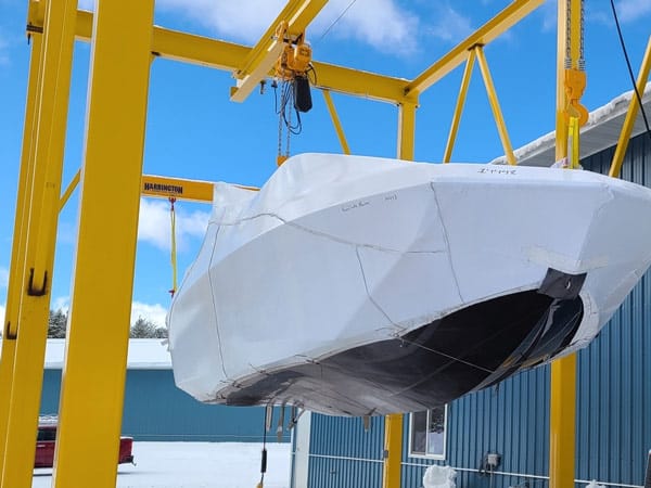 A yellow monorail crane lifts a boat.