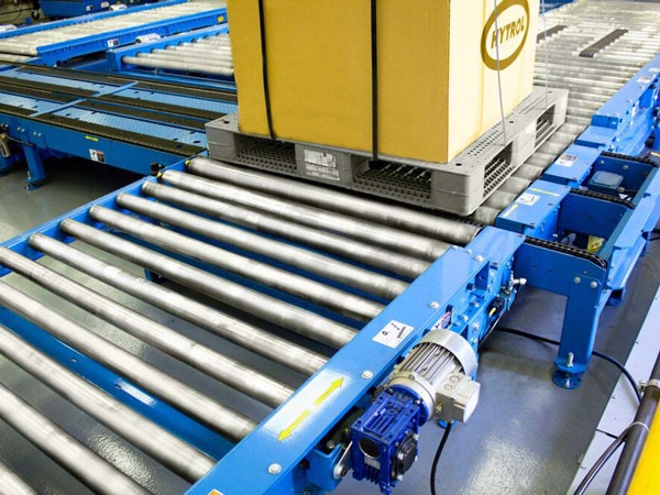 A pallet moves on a chain-driven roller conveyor.