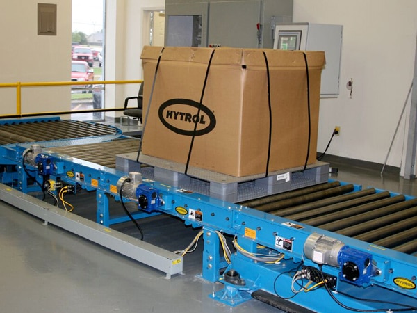 A pallet moves on a chain-driven roller conveyor.